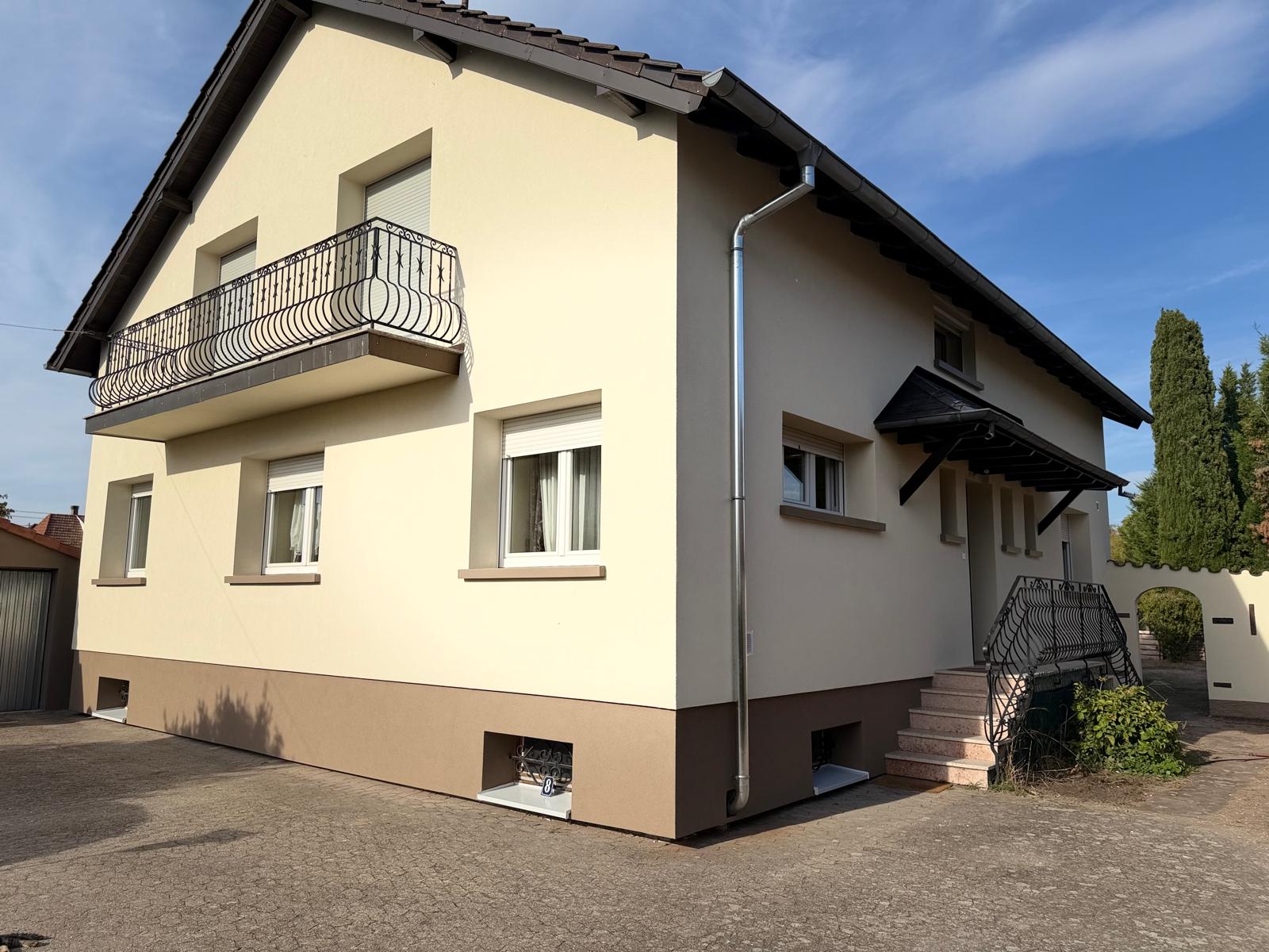 Façade de maison en limite de parcelle en cours d'isolation par l'extérieur, illustrant la question du surplomb sur le terrain voisin